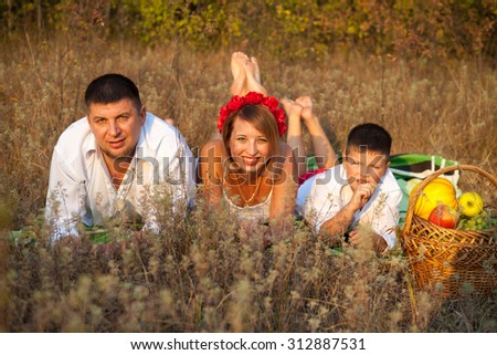mom dad and son lie on the rug next to each other in the park outdoors