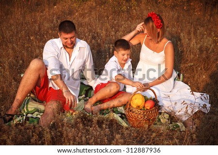 mom dad and son sitting on a picnic rug in a park