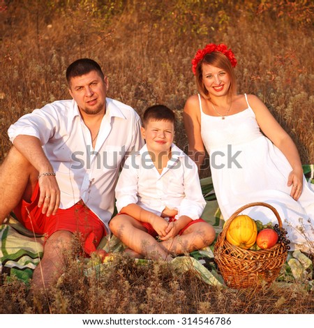 mom dad and son sitting on a picnic rug in a park
