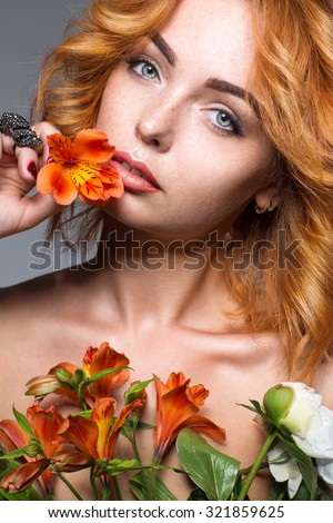 adorable woman with red hair and flowers with makeup posing on the gray background