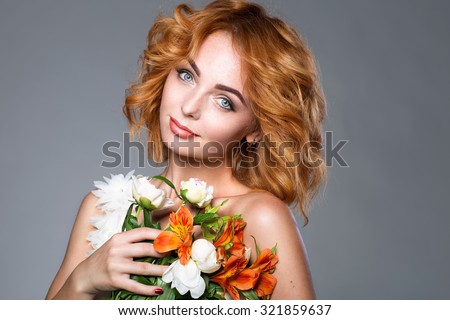 adorable woman with red hair and flowers with makeup posing on the gray background