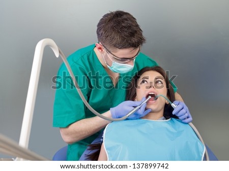 The confident dentist drilling the patient\'s teeth