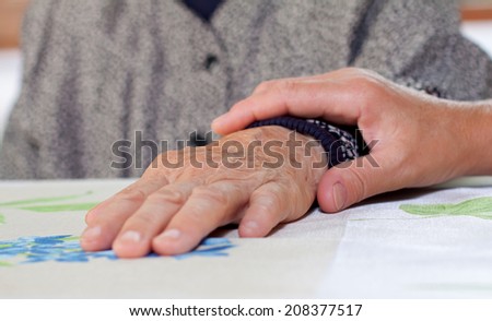 Doctor\'s hand holding a wrinkled elderly hand