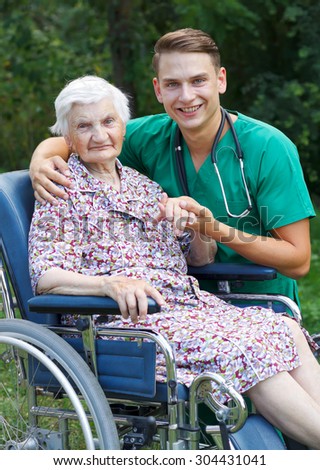 Young doctor helping a handicapped elderly woman