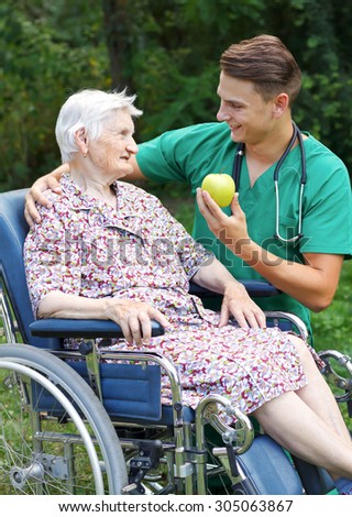Young doctor helping a handicapped elderly woman