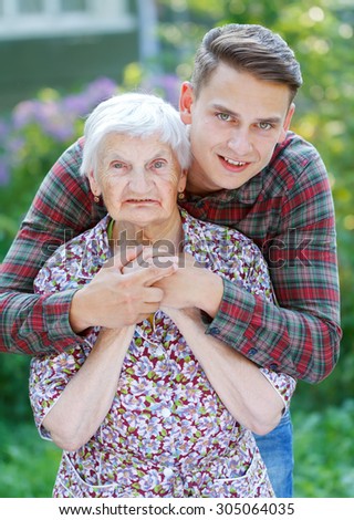 Grandson hugging her beautiful  senior wrinkled grandmother