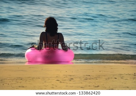 Women with pink ring at the ocean
