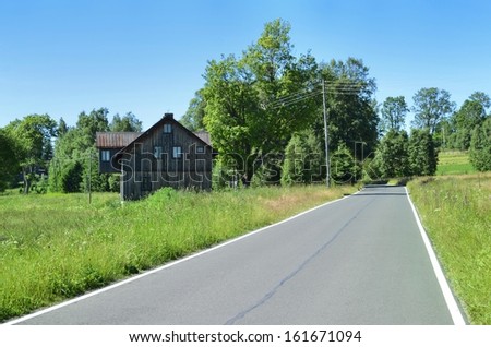 Road and old wooden house near forrest