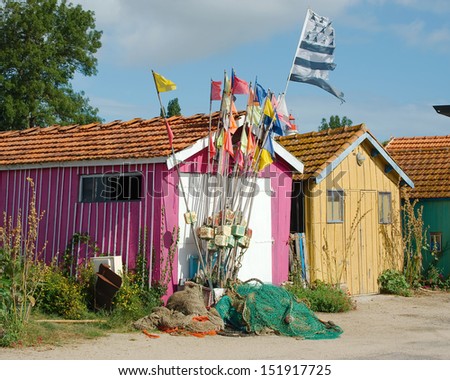 French fishing cabin with flags festooned outside and nets piled on the ground