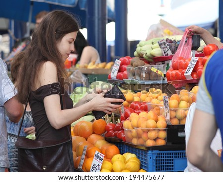 Shopping at the market. Girl is buying fruits on market. Woman is counting if she has enough money for the purchase.
