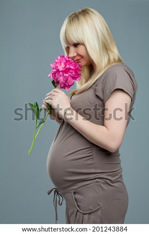 Pregnant woman smelling flowers. Portrait of pregnant woman in brown dress.