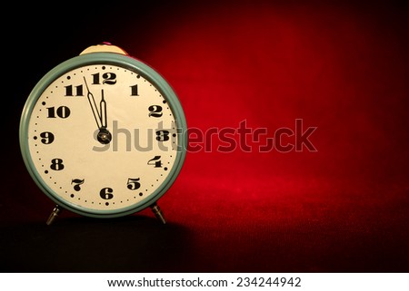 New Year background. Vintage clock on red-black background. Twelve o\'Clock on New Year\'s Eve against a red light spot.