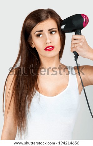 Beautiful woman holds a Hairdryer as the pistol to her temple