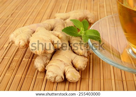 Ginger with gingertea-ingwertee on wooden mat with mint on wooden background