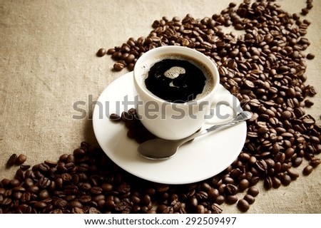 Wave made of coffee beans with cup of coffee with foam on linen,flax