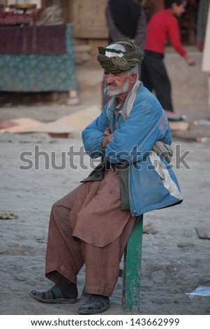 FAIZABAD, AFGHANISTAN - NOVEMBER 13:Unidentified old man with turban and beard watches ISAF troops passing by in the main street of Faizabad in the far north east of Afghanistan on November 13, 2011
