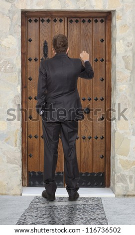 Businessman knocking at a wooden door
