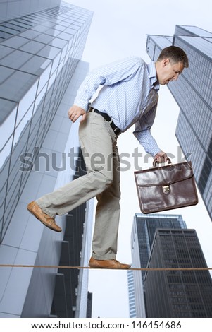 Businessman keeping his balance on a rope over a big city