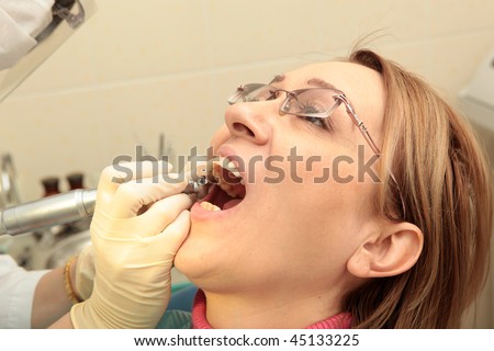 Close-up of woman with open mouth being examined by hygienist
