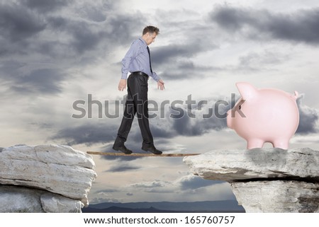 Businessman goes over the precipice to the pig piggy bank