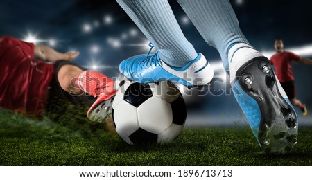 Football player man in action on dark arena background. Soccer player making sliding tackle