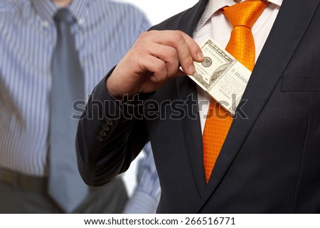 Businessman putting money in suit jacket pocket, concept for corruption, bribing