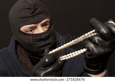Thief. Man in black mask with a pearl necklace. Focus on thief