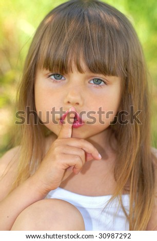 Small beautiful girl with a finger at her mouth