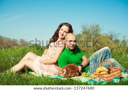 Married pregnant couple with dog at the picnic