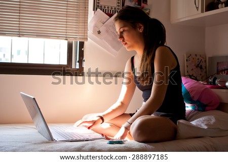 Teen surfing the net in bedroom