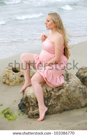 Portrait of beauty young woman in pink dress posing at a beach on sea background
