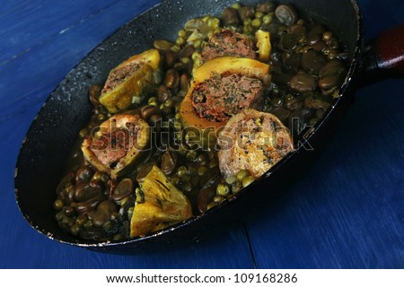 homemade cuisine: zucchini filled meat on peas and beans cooked into pan over blue wood