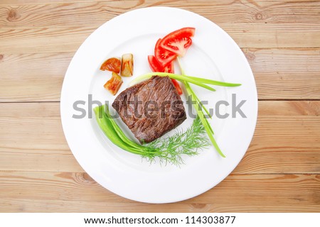 meat savory : grilled beef fillet mignon on white plate with tomatoes apples and pepper over wooden table