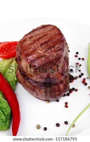 grilled beef fillet pieces on noodles , red hot chili pepper with tomato and green salad leaf on white plate isolated over white background