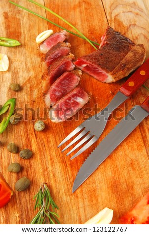 fresh roasted beef meat steak sliced on wooden board with cutlery isolated  over white background