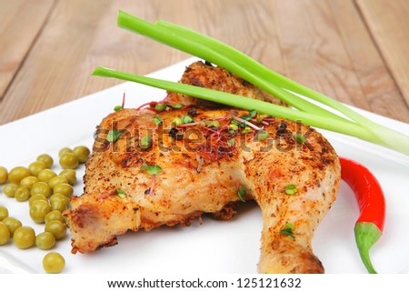 roast meat : roasted chicken legs garnished with green peas , peppers , and garlic on white plates over wooden table