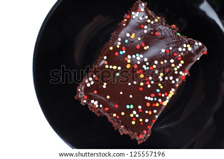 dessert : chocolate cake coated with chocolate on black saucer isolated over white background