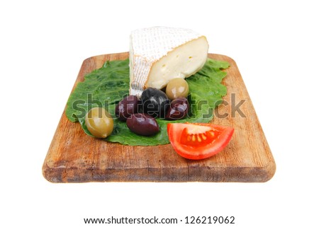 aged brie cheese on wooden platter with olives and tomato isolated over white background