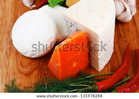 several soft and hard types of french cheese on wooden board with hot peppers and dill isolated on white background