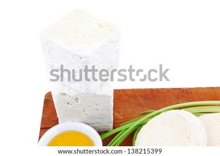 dairy product : fresh raw white soft greek feta cheese cubes and round on wooden plate isolated over white background
