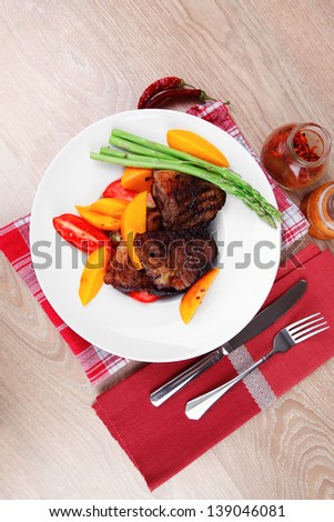 meat food : rare medium roast beef fillet with mango tomatoes and asparagus , served on white dish on red table map over wooden table