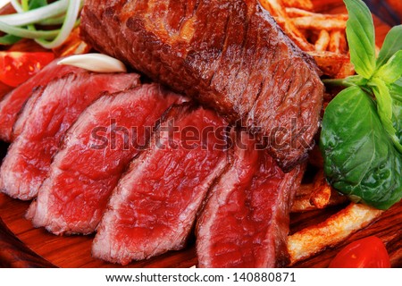 roast steak on potato : fresh grilled beef meat on wood plate with pepper and tomato isolated on white background