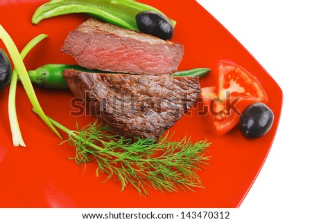 meat food : roasted fillet mignon on red plate with tomatoes apples and chili pepper isolated over white background