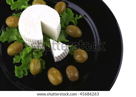 soft feta cheese on black dish with gold olives