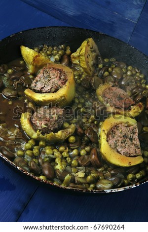 homemade cuisine: zucchini filled meat cooked with peas on black pan over blue