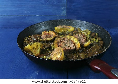 homemade cuisine: zucchini filled meat cooked with peas, beans, on pan over blue