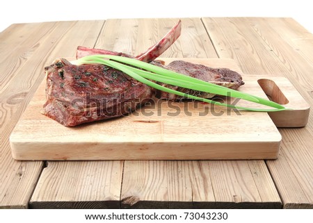 served main course: boned roasted lamb ribs served with green chives on wooden board