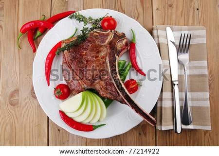 savory : grilled spare rib on white dish with thyme pepper and tomato on wooden table