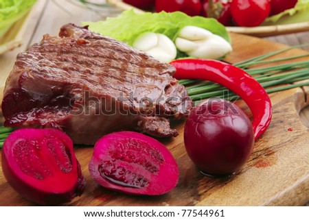 bbq : beef (pork) steak garnished with green staff and red chili hot pepper on wooden table with cutlery