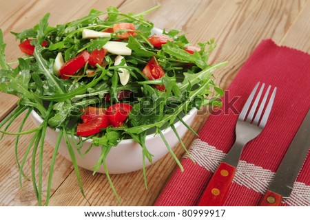 healthy food : salad with raw tomato , garlic , and green staff in white bowl over wood served with cutlery